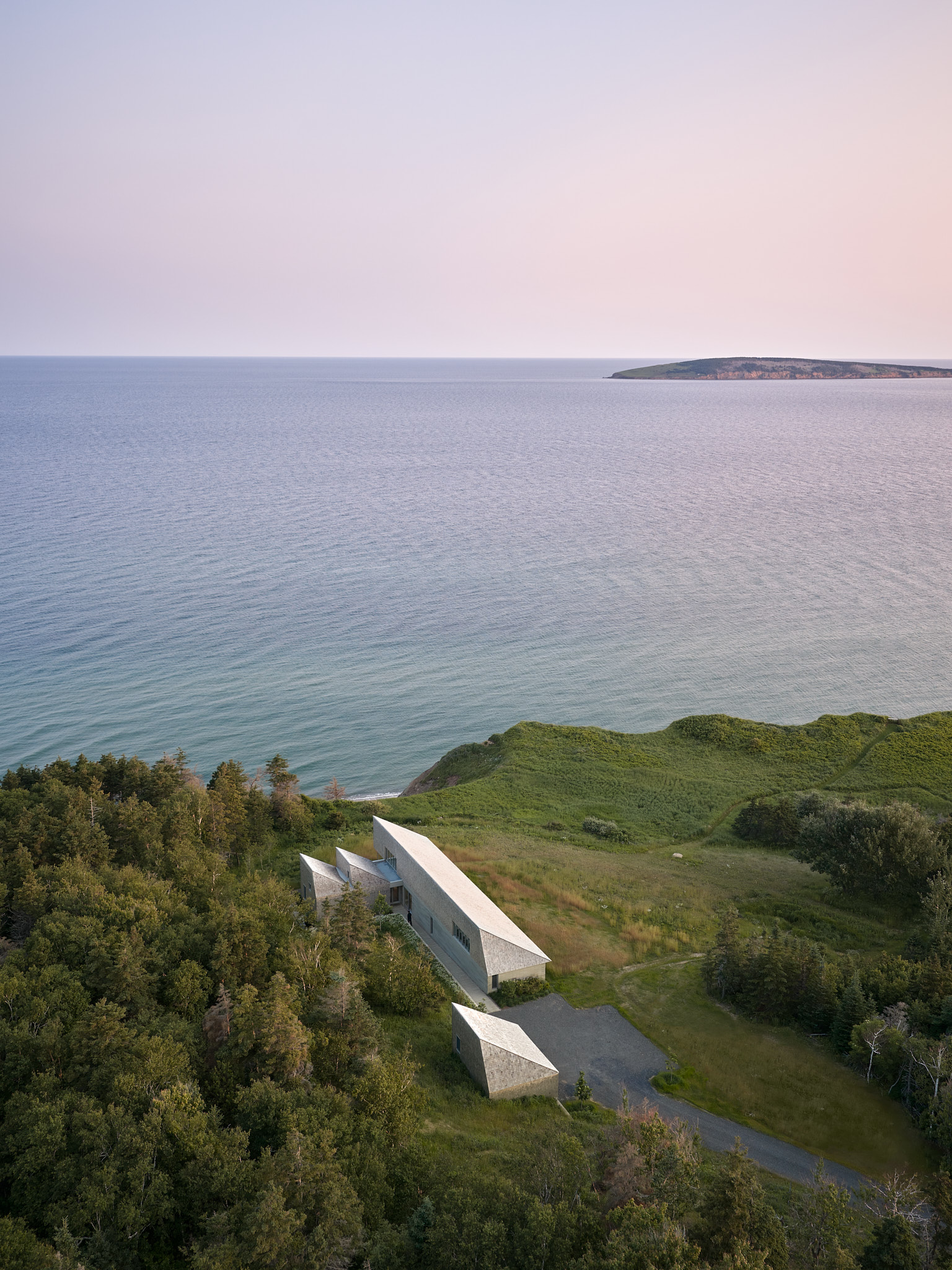 place of work's house in a meadow between the forest and the sea, an architectural, geometric house in leafy countryside