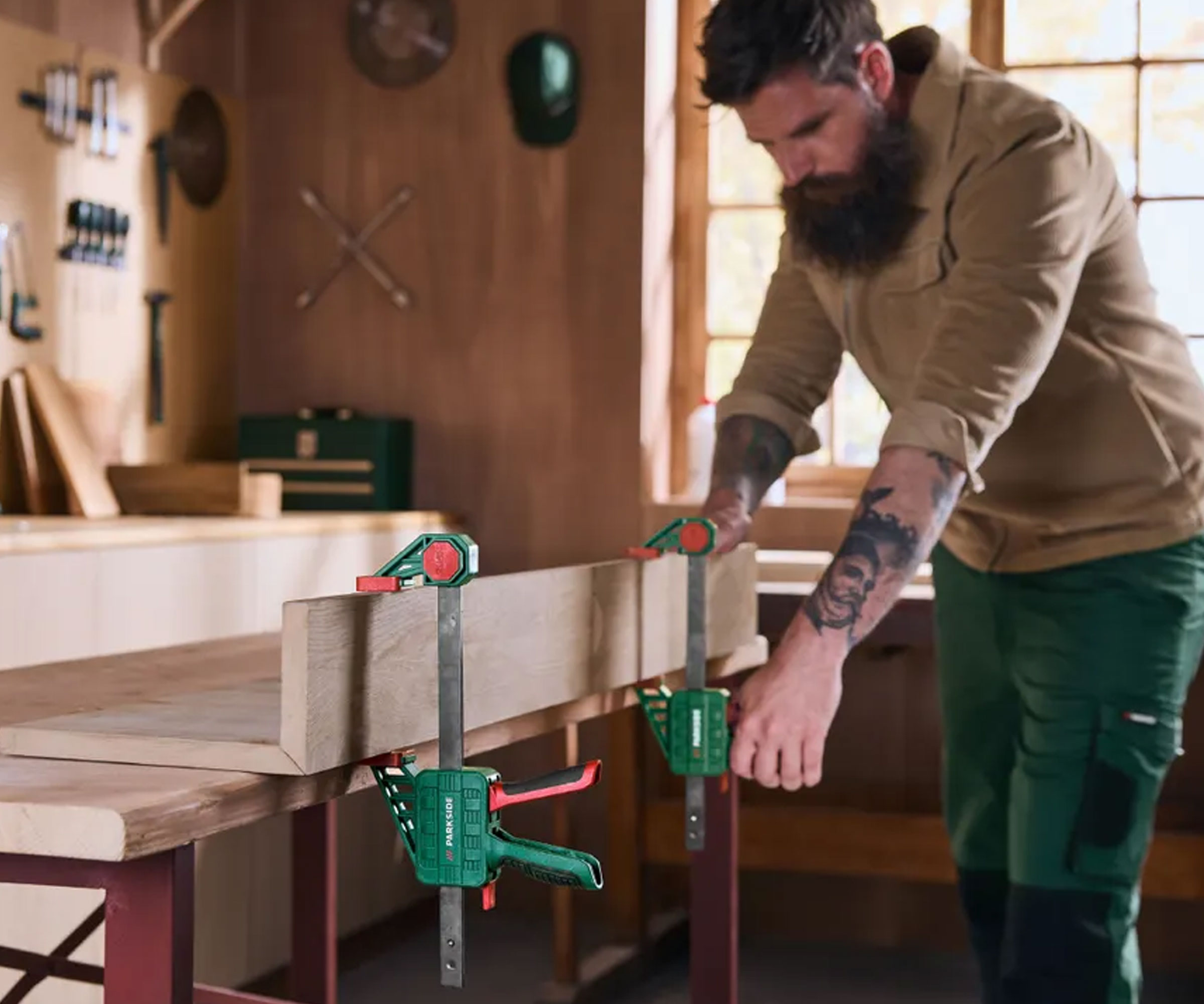 Man using large bar clamps to hold wood in place on bench