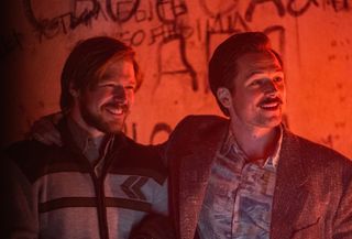 (L to R) Taron Egerton as Henk Rogers and Nikita Efremov as Alexey Pajitnov, smiling in a club, in Tetris