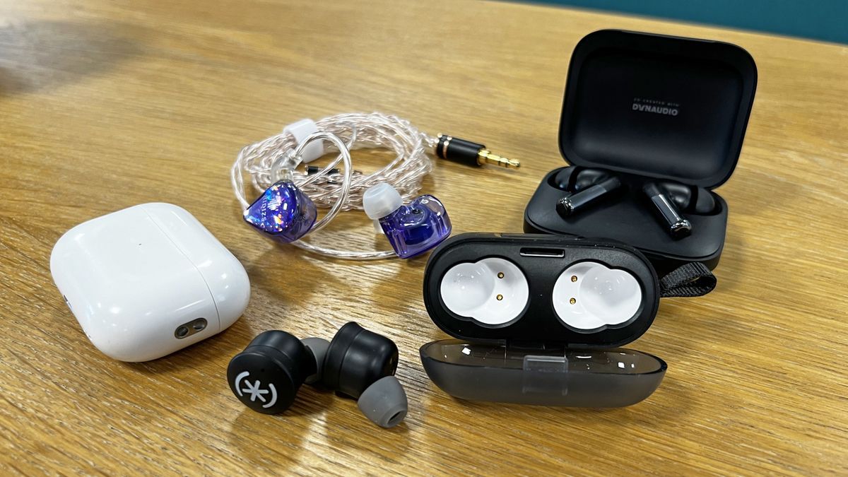 A group of wired and wireless earbuds on a wooden table