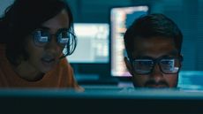 Concept image showing two cybersecurity workers in a dimly lit room symbolizing CISA hackers.