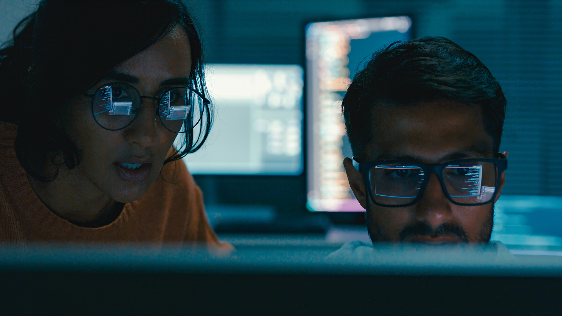 Concept image showing two cybersecurity workers in a dimly lit room symbolizing CISA hackers.