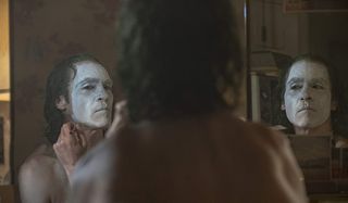 Joker Arthur paints his face as a transformation