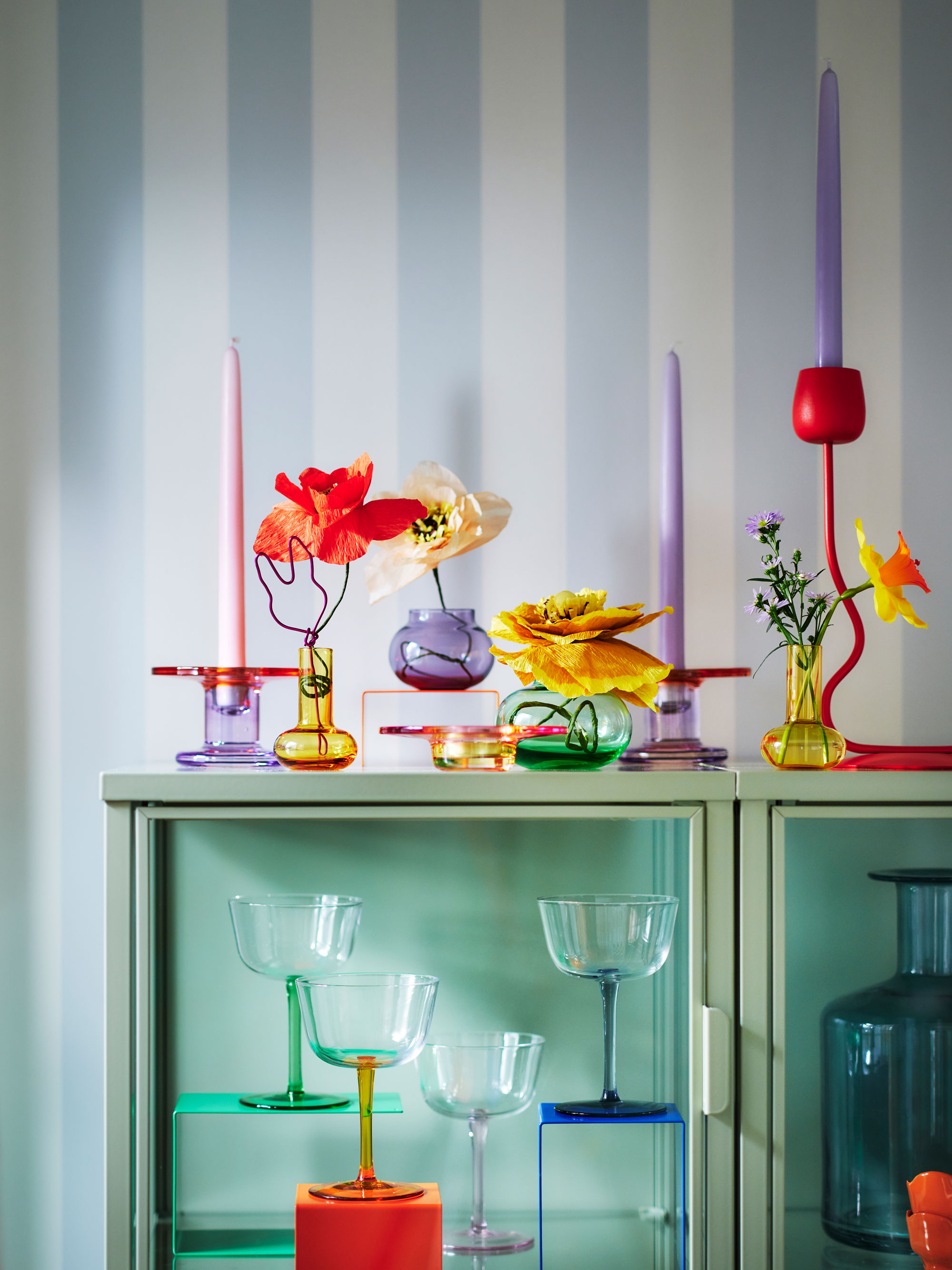 a collection of colorful candle sticks and vases on a table