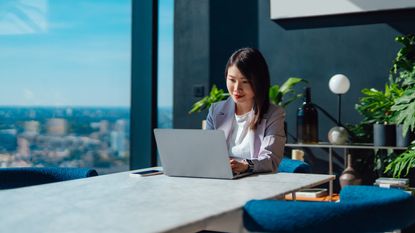 A financial adviser smiles as she works on her laptop in her office.