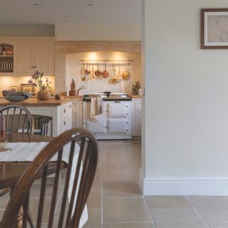 country kitchen with cream cabinetry and walls with white aga and stone mullion windows Harvey Jones