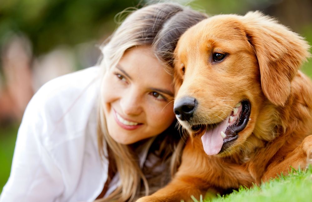 Portrait of a woman with her beautiful dog lying outdoors