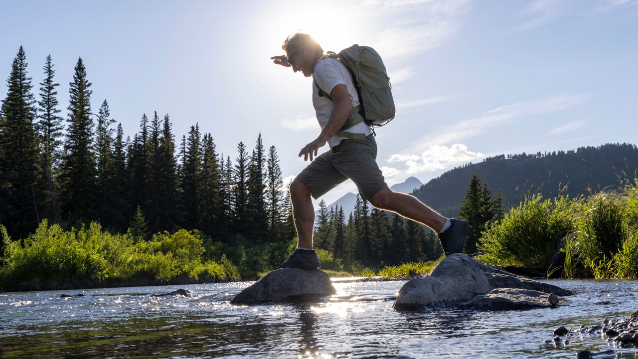 Man jumping from stone to stone in a river