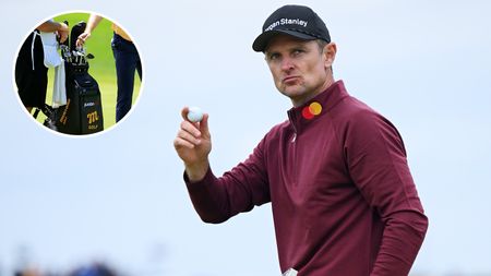 Justin Rose waves to the crowd in a red hoodie