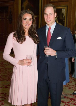 Kate Middleton wearing a pink dress with Will.