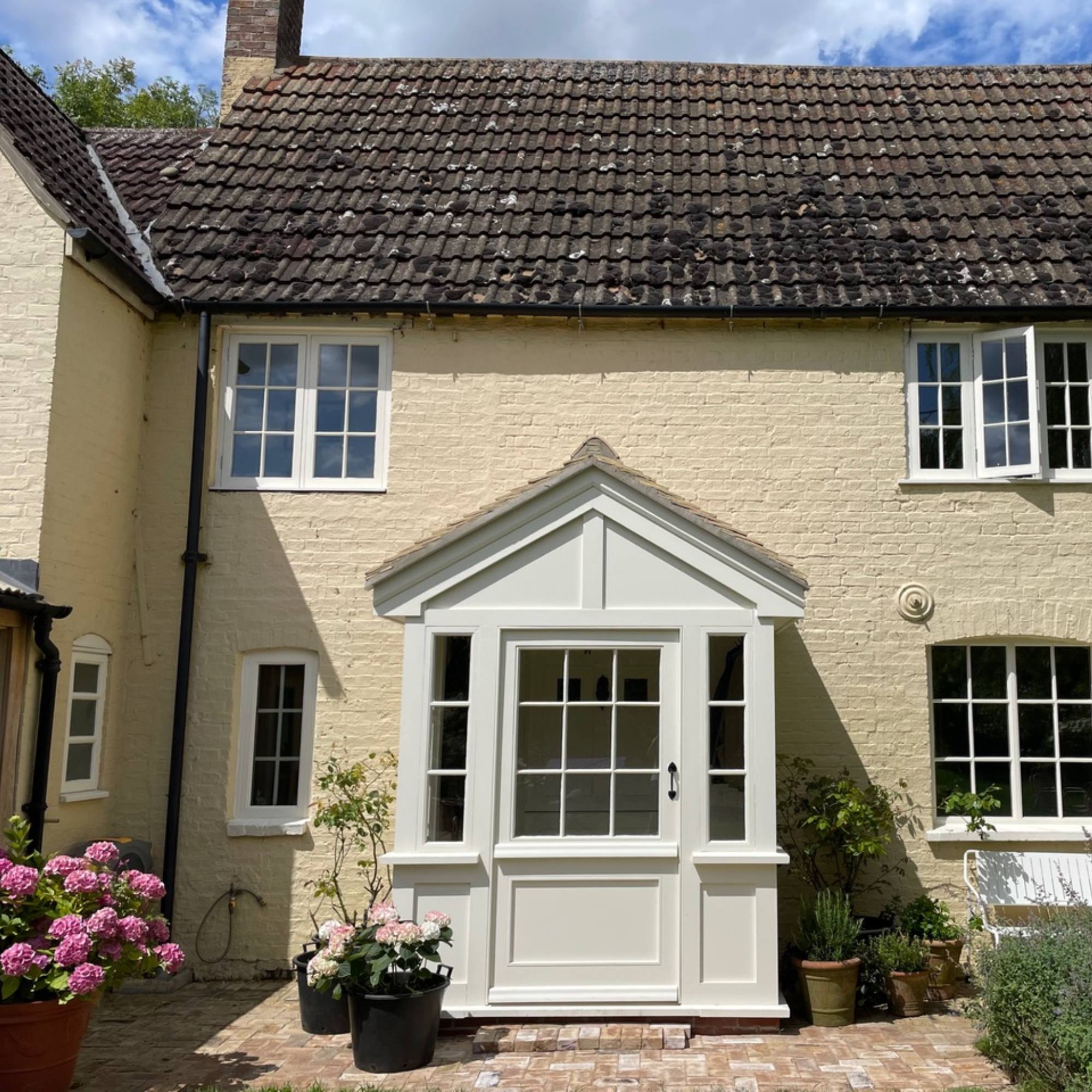 cream coloured enclosed porch to traditional cottage painted pale yellow