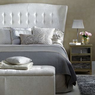 bedroom with grey fabric on headboard and mirrored side table