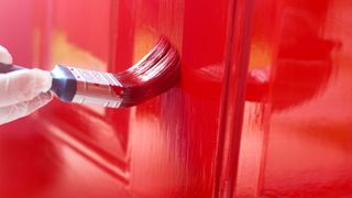 Paintbrush painting front door in red gloss