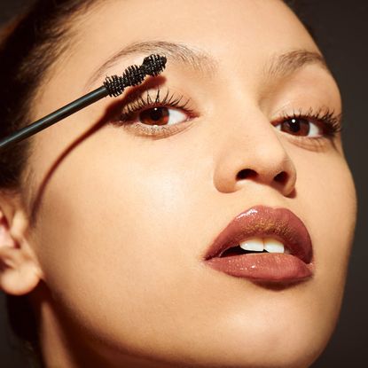 woman sweeping mascara onto her eyelashes