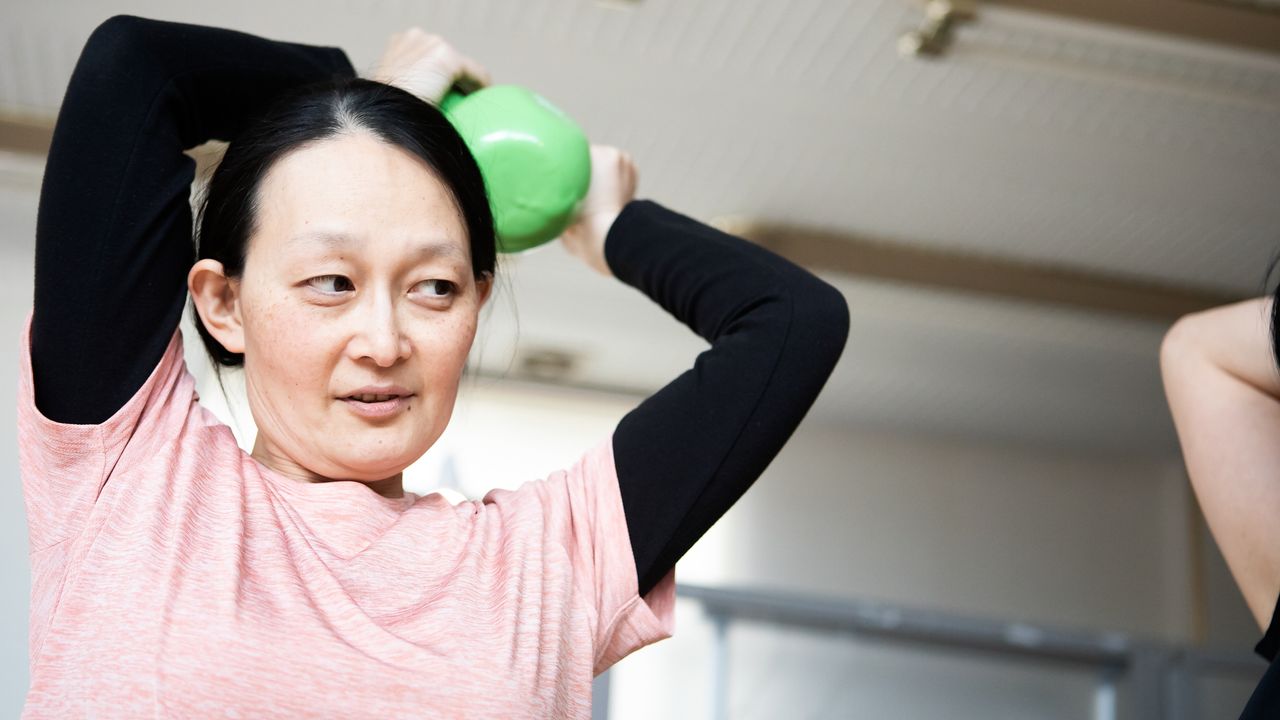 Woman holds kettlebell near her head