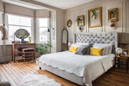 vintage bedroom with paneling, buttoned headboard and vintage frames on the wall
