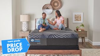 A couple sitting on a Sealy Posturepedic mattress