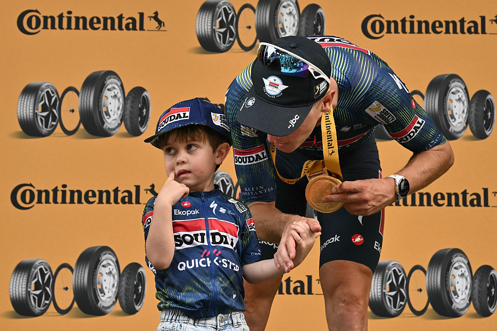 Tim Merlier celebrates on the podium with his son Jules after winning the 12th stage