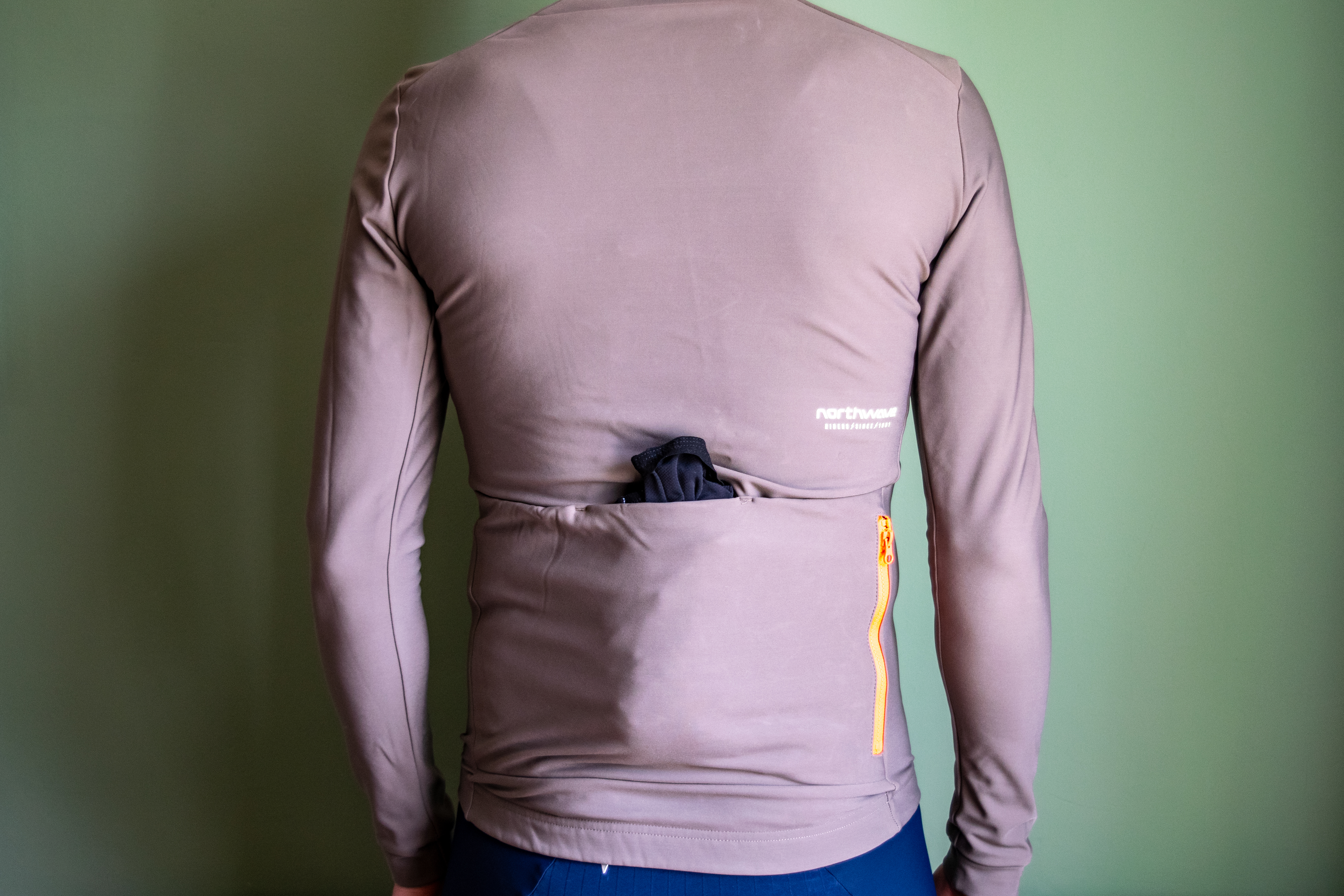 A man wearing a black Assos Tactica gilet over a grey long sleeve shirt