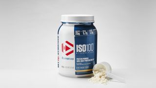 Dymatize Nutrition ISO100 on a table with some powder dispersed in front