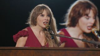 A screenshot of Taylor Swift singing at the piano during the Eras Tour.