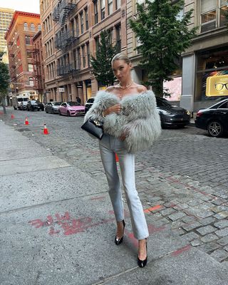 Elsa Hosk wearing a furry jacket with light-wash jeans and black pumps in NYC