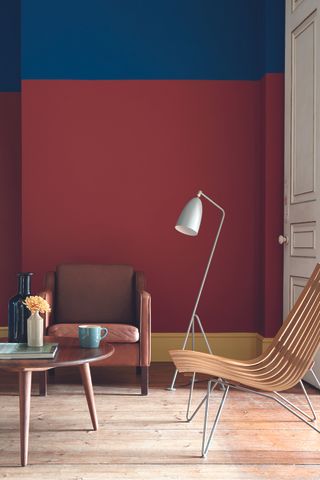 Red Living room with two armchairs and coffee table, floor lamp and wall painted in red and blue with yellow skirting board