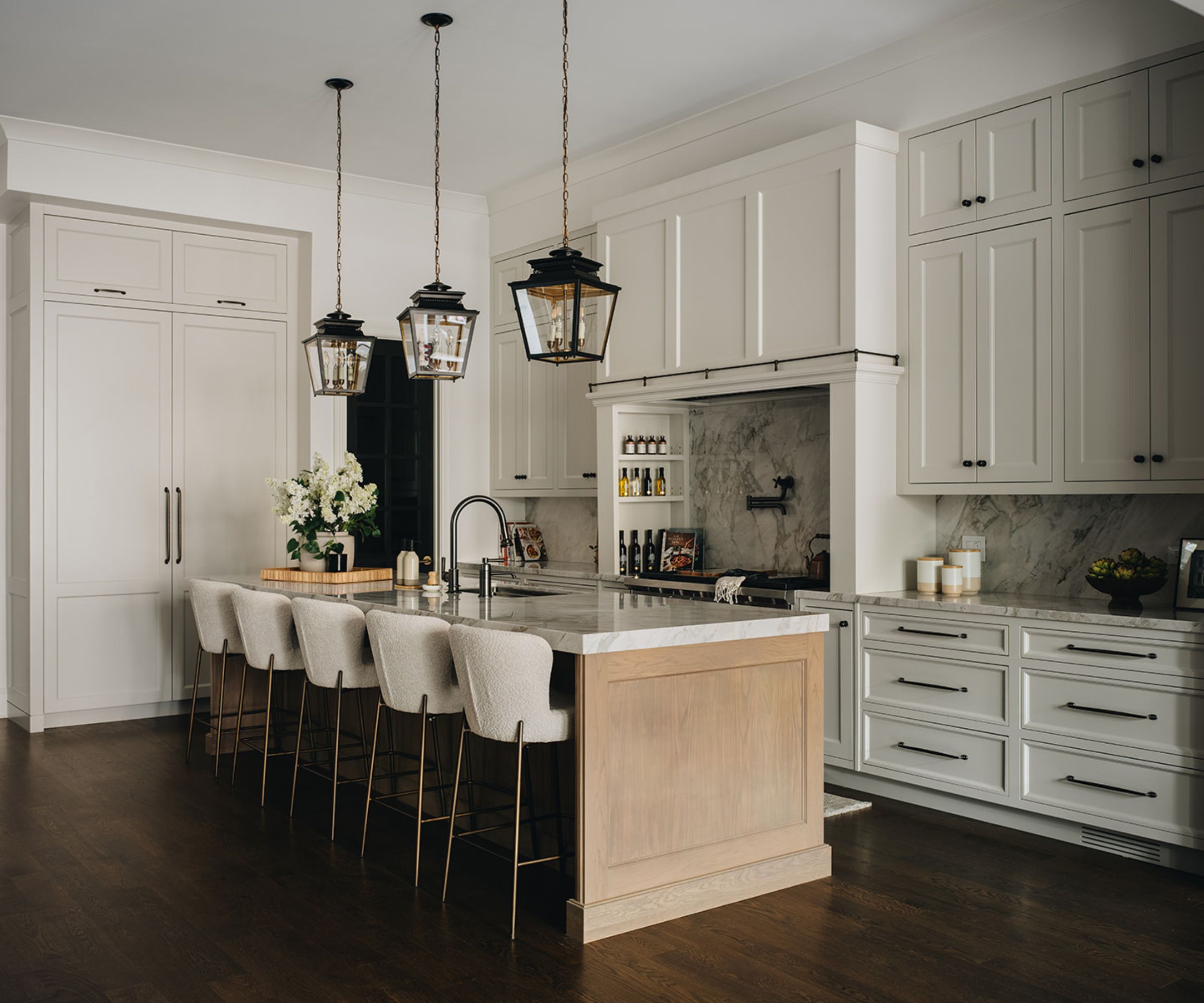 A kitchen with warm white cabinetry, a wooden island, and lantern-style lighting
