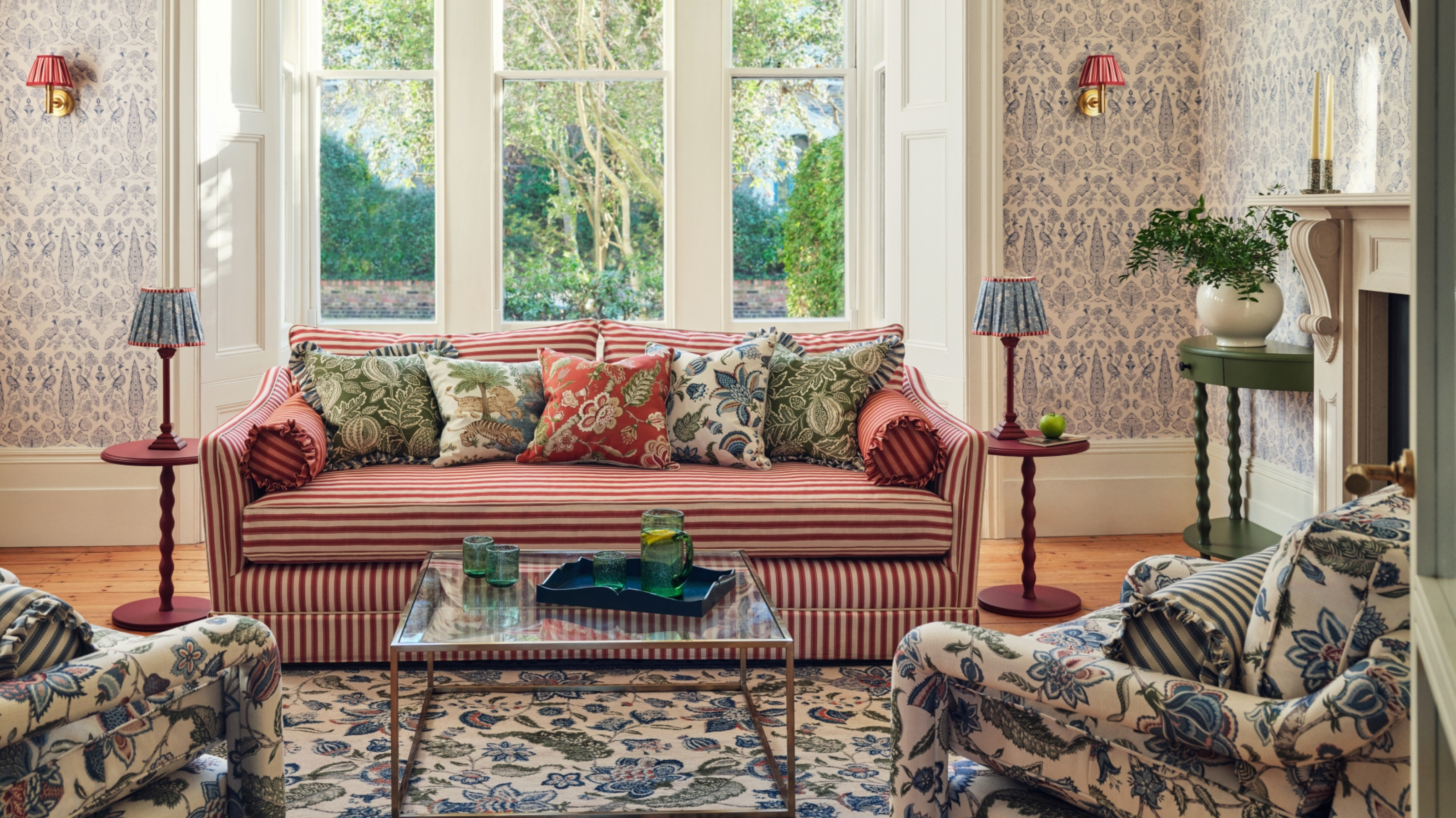Living room featuring sanderson wallpaper, rugs and red striped sofa.