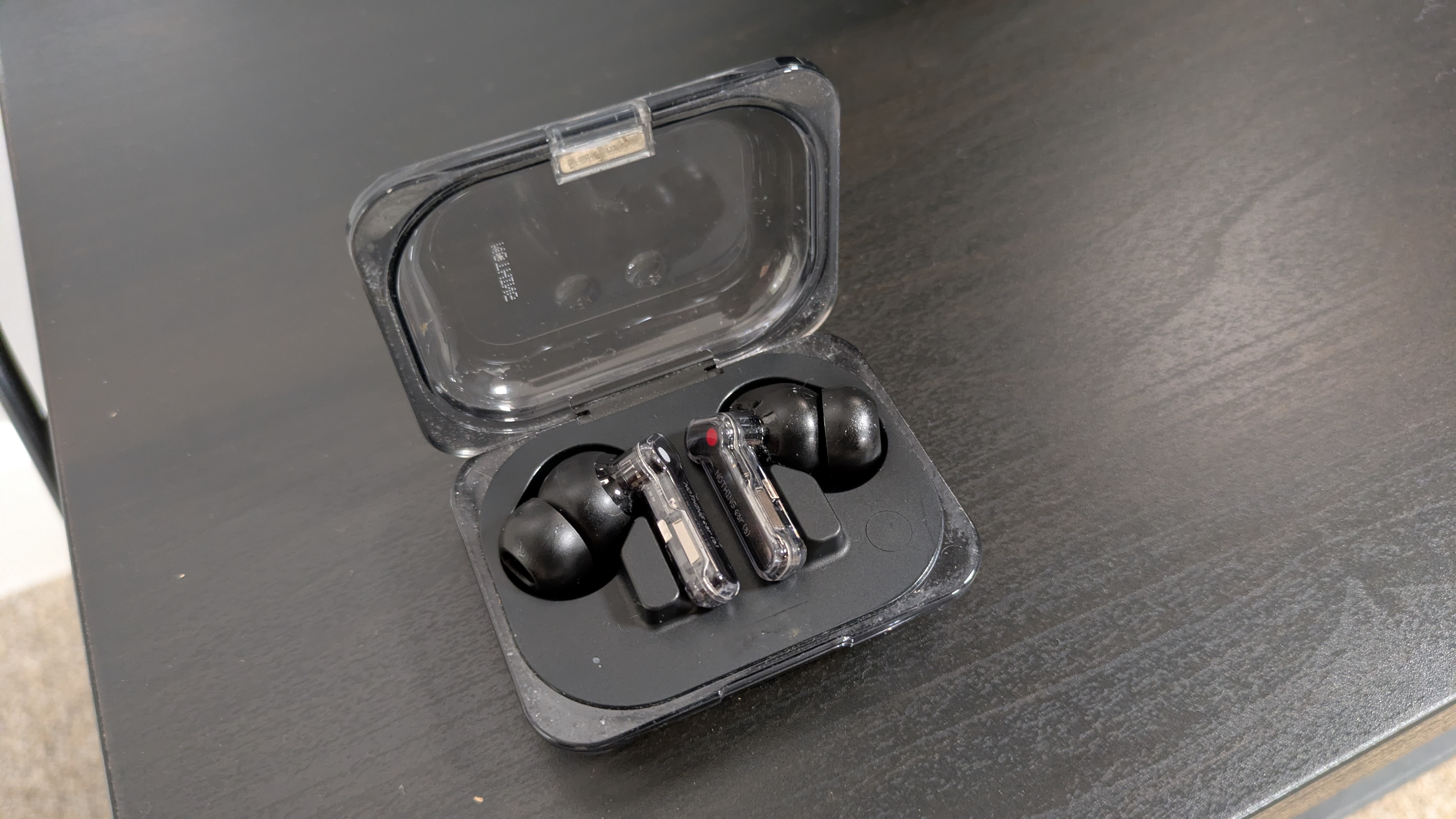 Nothing Ear (a) earbuds on dark wood bench