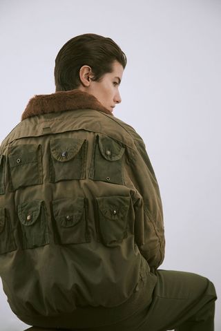 Model wearing an oversized, square cut field jacket and a trench coat with rounded pockets