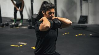 Woman holding two dumbbells by her shoulders