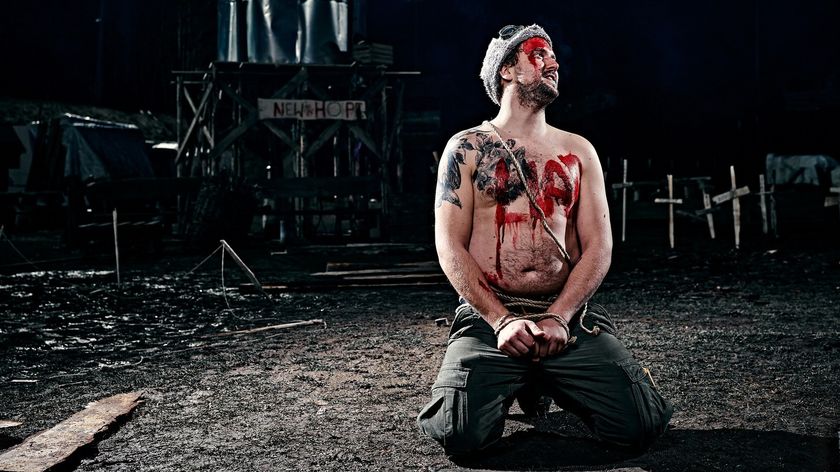 A shirtless man kneels, handcuffed, with the word &#039;LIAR&#039; written in red paint across his chest.