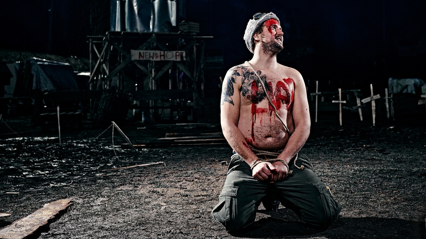 A shirtless man kneels, handcuffed, with the word &#039;LIAR&#039; written in red paint across his chest.