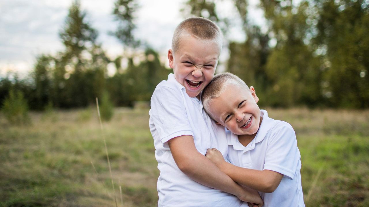 Two young brothers hug.