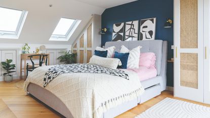 A peach-painted attic bedroom with a tonal bedspread on the bed and downlights at the ceiling