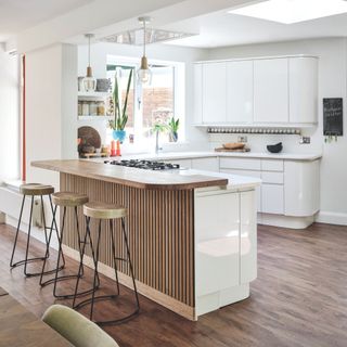 White kitchen with wooden breakfast bar and gold stools