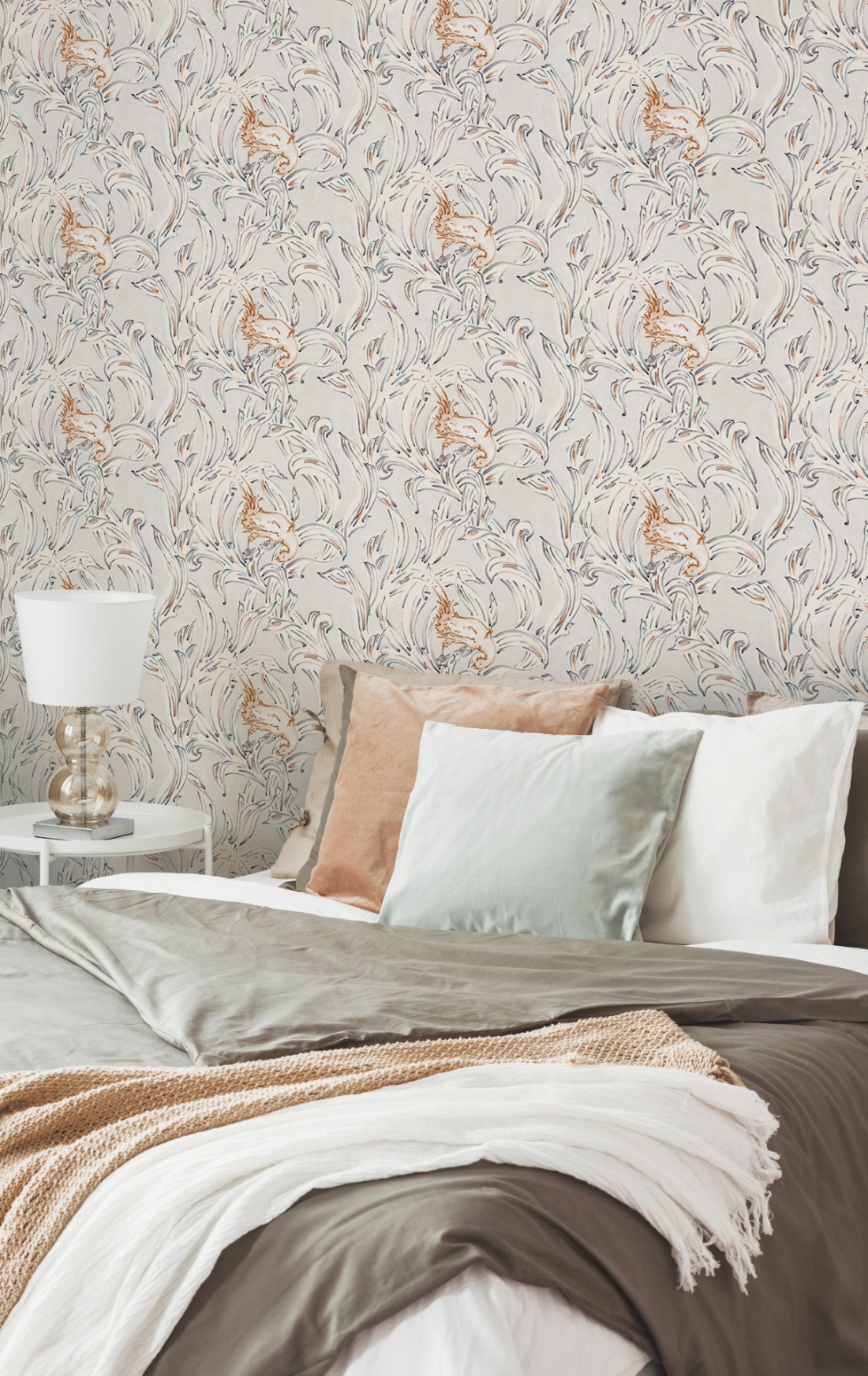 Salmon pink and light grey bedding with soft patterned bedroom wallpaper and white side lamp