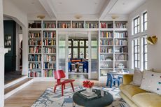 A living room with a bookshelf wall partition with an open doorway leading on to another living space