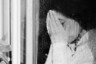 A woman looks out a window during a dreary winter day.