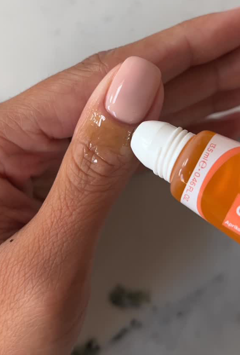 A close up of Iram Shelton applying a cuticle oil to her nails