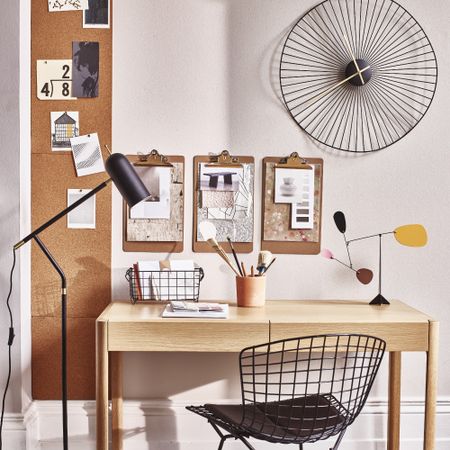 A home office with a light wooden desk, a black metal wire chair and a matching desk organiser