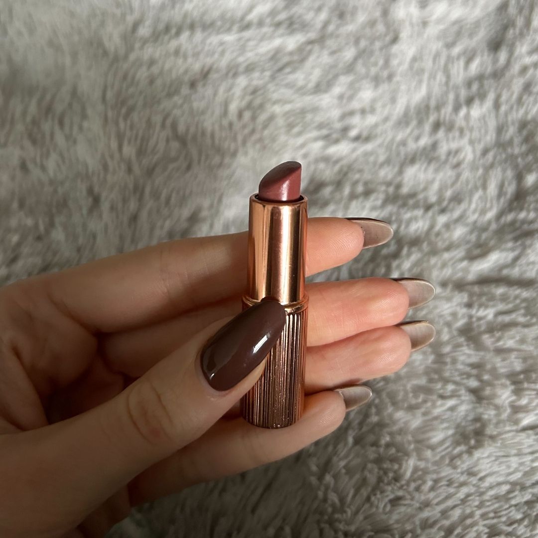 Image of Charlotte Tilbury Pillow Talk Lipstick in hand with brown nails