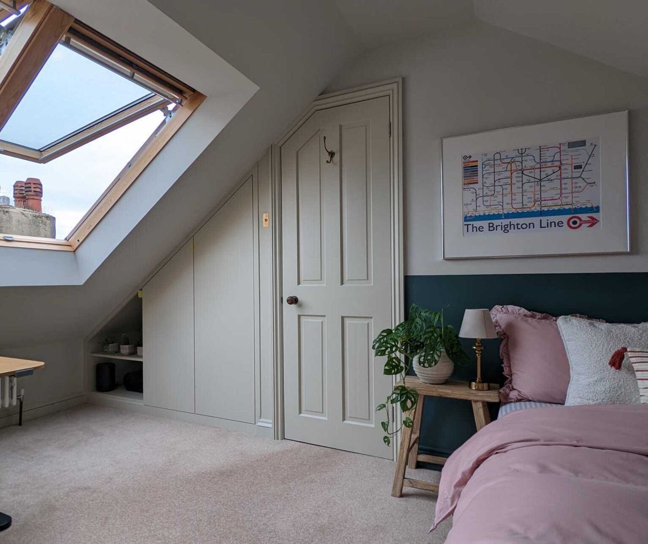 An attic bedroom with skylights and a wardrobe built-in to an alcove