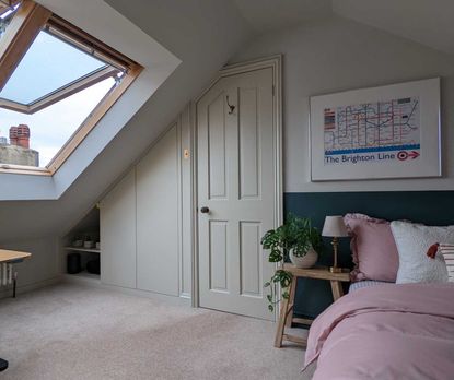 An attic bedroom with skylights and a wardrobe built-in to an alcove