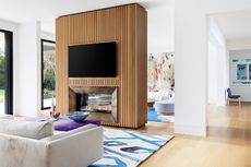 a living room with a slatted fireplace room divider with a fireplace