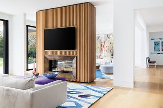 a living room with a slatted fireplace room divider with a fireplace