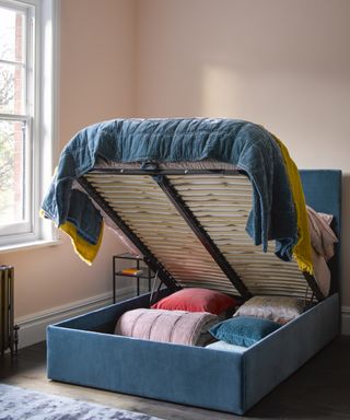 denim blue velvet ottoman bed open showing cushions and throws inside