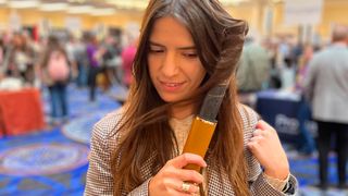 A woman holds a hair styling tool up to her hair