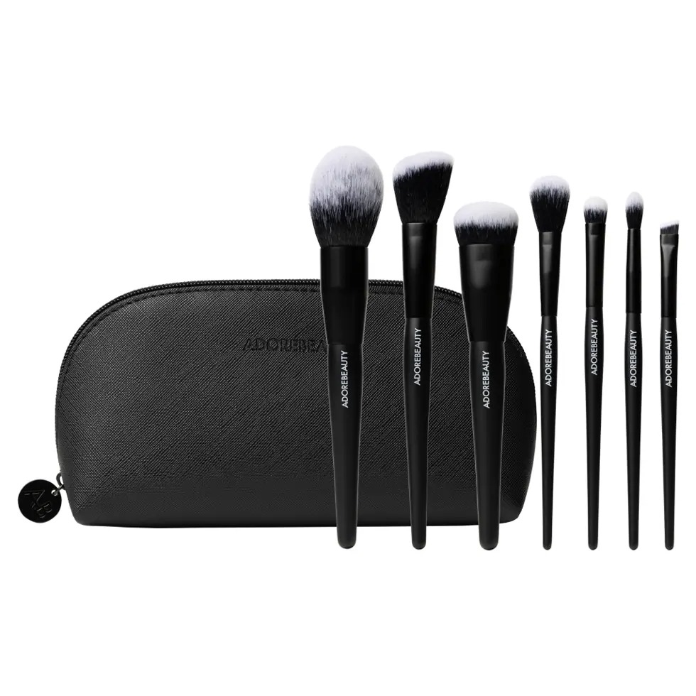 Black leather makeup bag with seven black makeup brushes in front of it